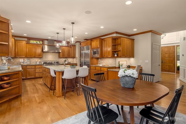 dining space featuring sink, ornamental molding, and light wood-type flooring