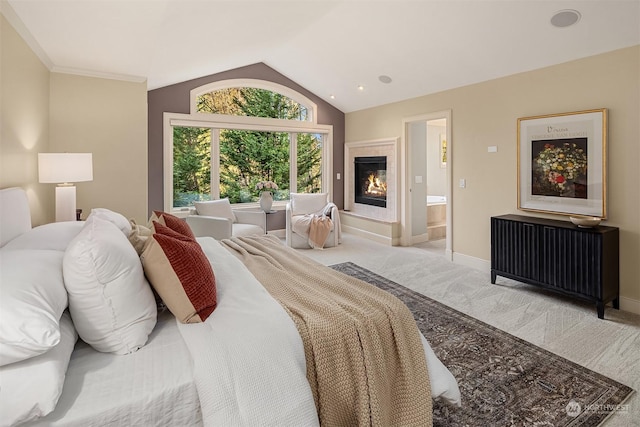 bedroom with vaulted ceiling, light carpet, and ensuite bath