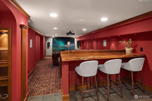 bar with crown molding, ornate columns, and wood counters