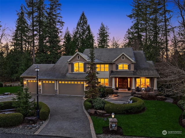 view of front of property featuring a garage, concrete driveway, and a lawn