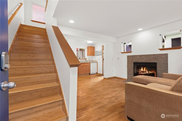 staircase featuring sink, a fireplace, and wood-type flooring