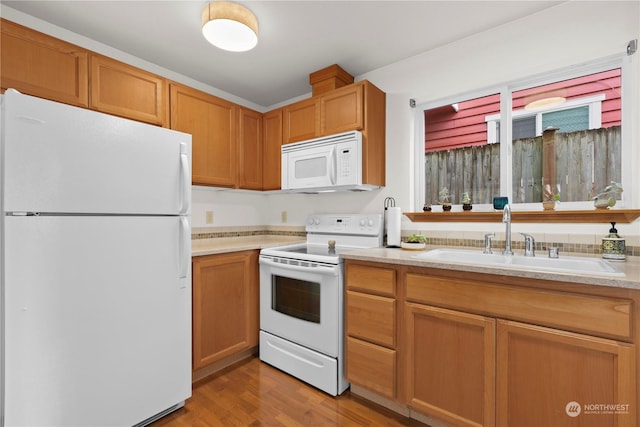 kitchen with white appliances, sink, and light wood-type flooring