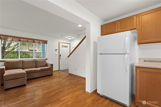 kitchen with light stone countertops, white fridge, and light hardwood / wood-style floors