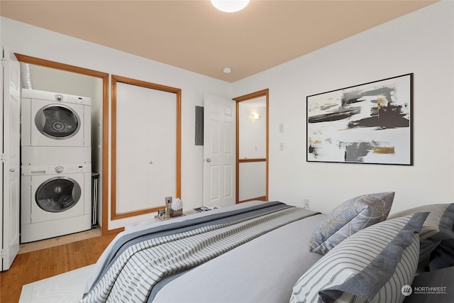 bedroom with stacked washer / dryer, electric panel, and light hardwood / wood-style flooring