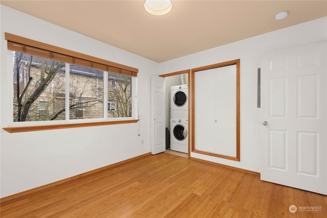 clothes washing area featuring stacked washer / drying machine and light hardwood / wood-style floors