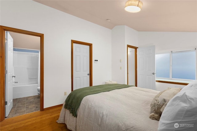 bedroom featuring ensuite bathroom, lofted ceiling, and hardwood / wood-style floors