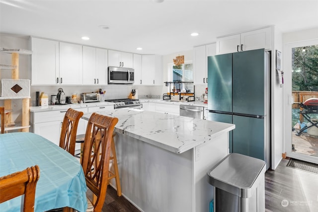 kitchen with appliances with stainless steel finishes, a kitchen island, and white cabinets