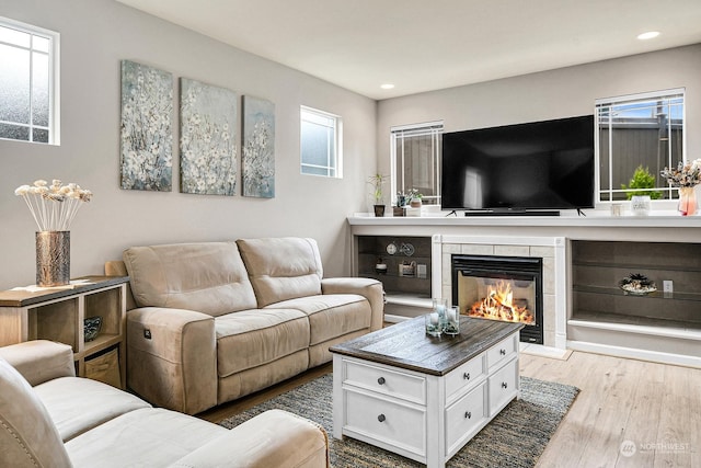 living room featuring a tiled fireplace and light hardwood / wood-style floors