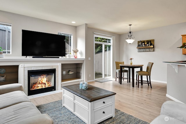 living room featuring a tile fireplace and light hardwood / wood-style flooring