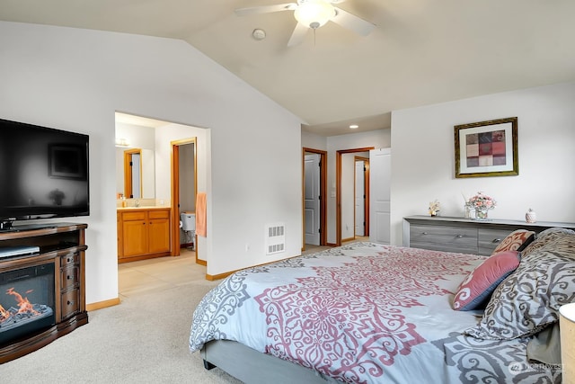 bedroom featuring ceiling fan, lofted ceiling, connected bathroom, and light carpet