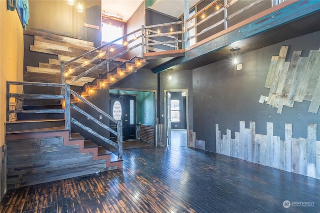 staircase with hardwood / wood-style flooring, a towering ceiling, and a healthy amount of sunlight