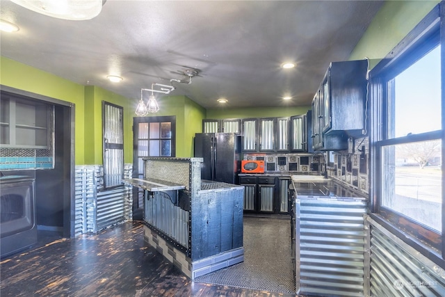 kitchen featuring sink, backsplash, hanging light fixtures, black fridge, and washer / clothes dryer