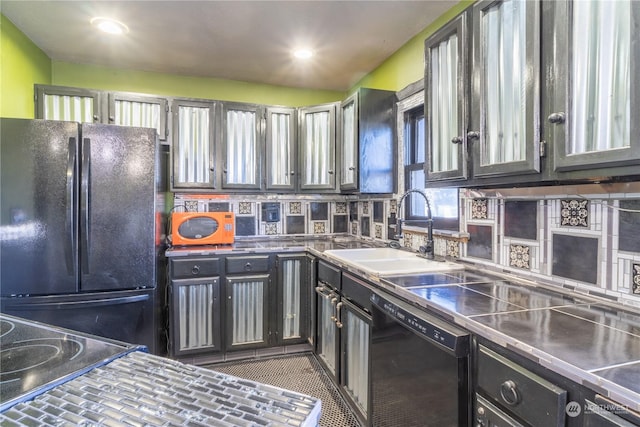 kitchen featuring dark tile patterned floors, sink, stainless steel counters, and black appliances