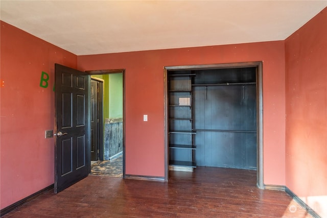 unfurnished bedroom with dark wood-type flooring and a closet