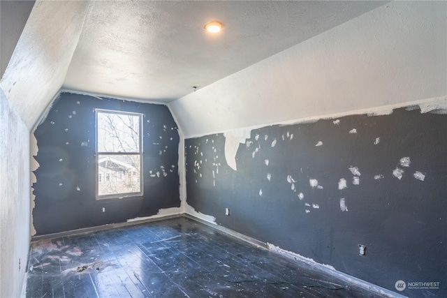 additional living space with lofted ceiling and a textured ceiling