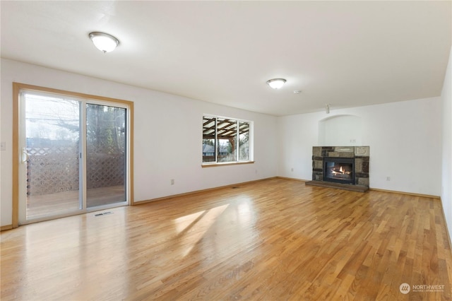 unfurnished living room featuring a stone fireplace and light hardwood / wood-style floors