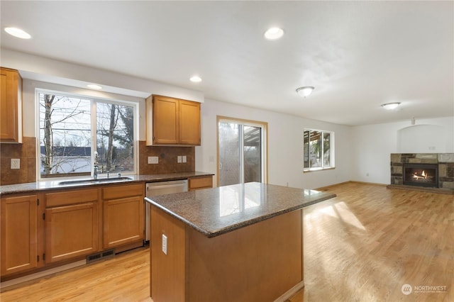 kitchen with sink, a kitchen island, light hardwood / wood-style flooring, and a fireplace