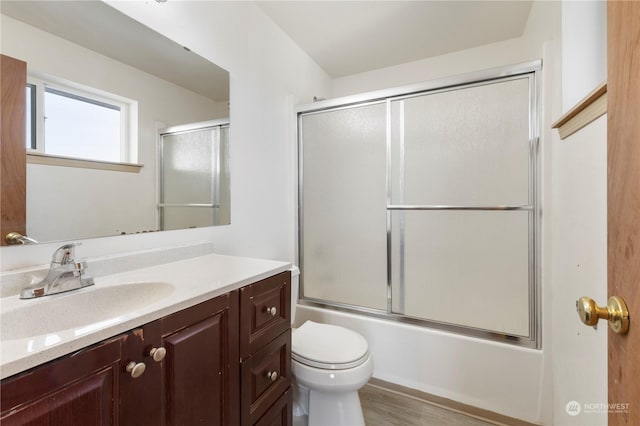 full bathroom with wood-type flooring, toilet, vanity, and shower / bath combination with glass door