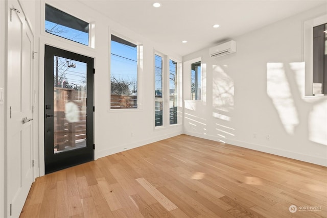 empty room featuring a wall mounted AC and light wood-type flooring