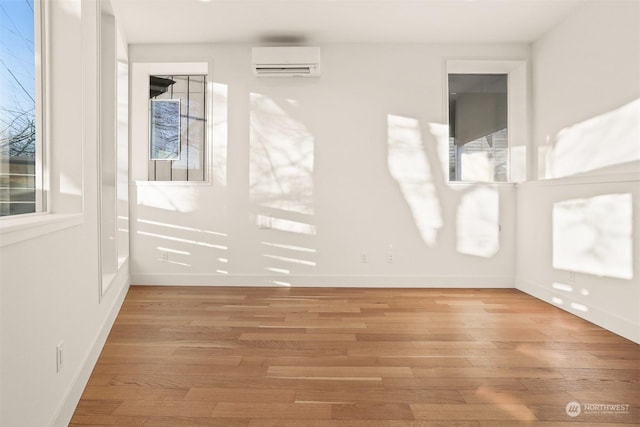 unfurnished room with a wealth of natural light, light hardwood / wood-style flooring, and an AC wall unit