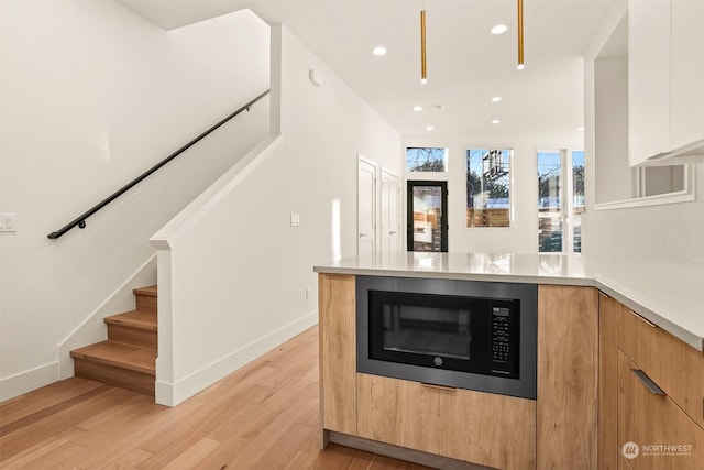 kitchen featuring black microwave, white cabinets, and light hardwood / wood-style floors