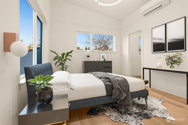 bedroom featuring light hardwood / wood-style floors and a wall unit AC