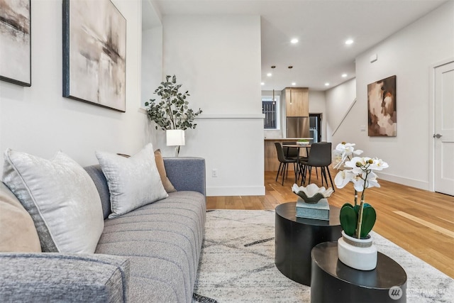 living area featuring baseboards, recessed lighting, and light wood-style floors