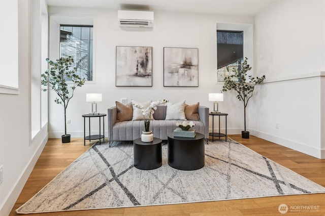 sitting room featuring plenty of natural light, light wood finished floors, and a wall unit AC