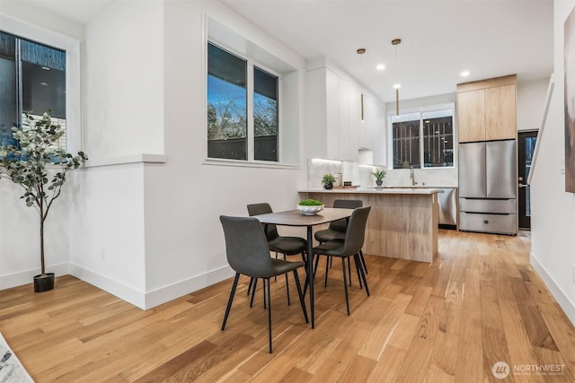 dining room with light wood finished floors, baseboards, and recessed lighting