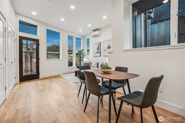 dining space with baseboards, light wood finished floors, a wall mounted AC, and recessed lighting