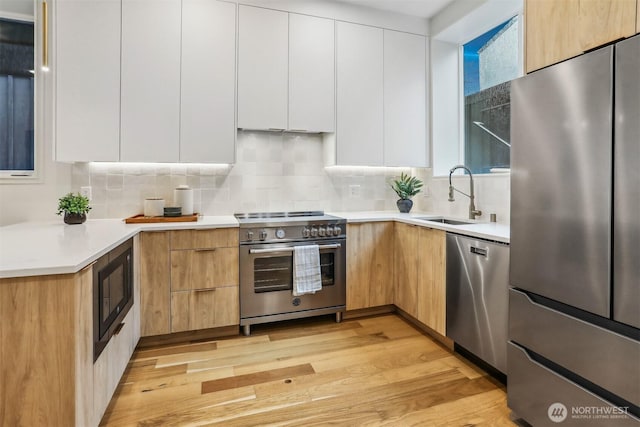 kitchen featuring appliances with stainless steel finishes, white cabinets, a sink, and light countertops