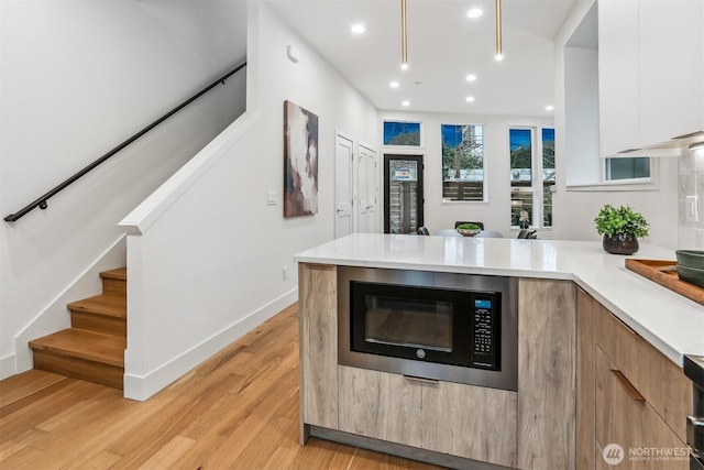 kitchen with black microwave, light countertops, modern cabinets, and white cabinetry