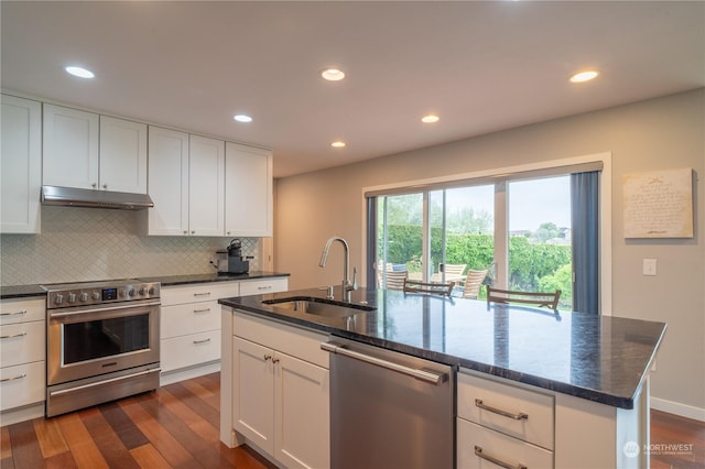 kitchen with an island with sink, white cabinetry, sink, dark hardwood / wood-style flooring, and stainless steel appliances