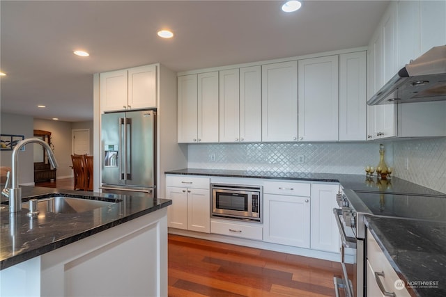 kitchen featuring white cabinetry, sink, dark stone counters, stainless steel appliances, and dark wood-type flooring