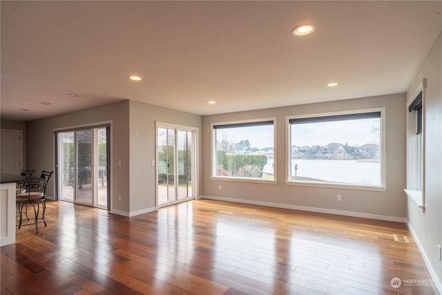 unfurnished living room featuring hardwood / wood-style flooring and a water view