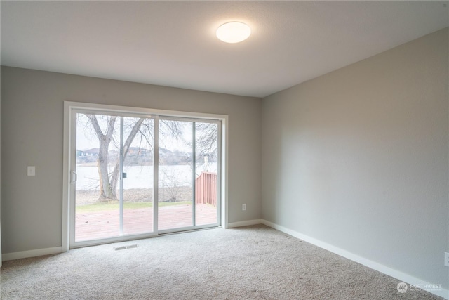 carpeted empty room featuring a water view