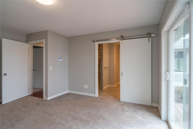 unfurnished bedroom featuring light carpet and a barn door