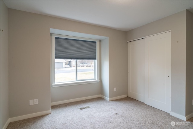 unfurnished bedroom with light carpet and a closet