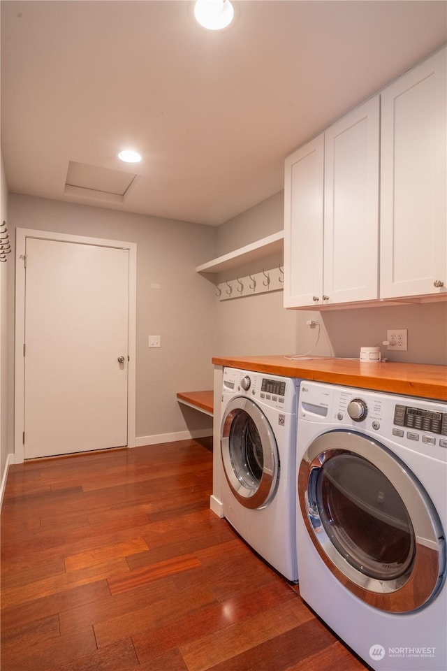 laundry area with dark hardwood / wood-style flooring, washer and clothes dryer, and cabinets