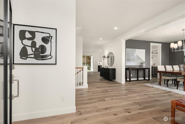 hallway featuring a notable chandelier, wood-type flooring, and built in features