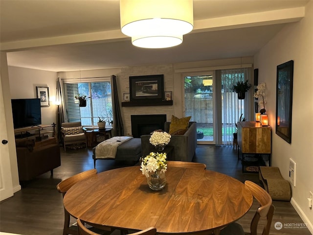 dining room with dark hardwood / wood-style flooring, beamed ceiling, and a fireplace