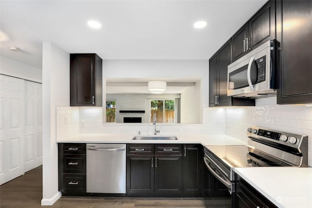 kitchen with sink, decorative backsplash, appliances with stainless steel finishes, and dark hardwood / wood-style flooring