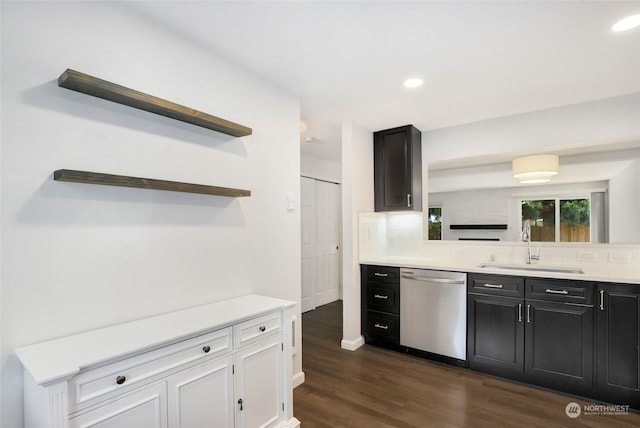 kitchen with tasteful backsplash, dishwasher, sink, white cabinets, and dark wood-type flooring