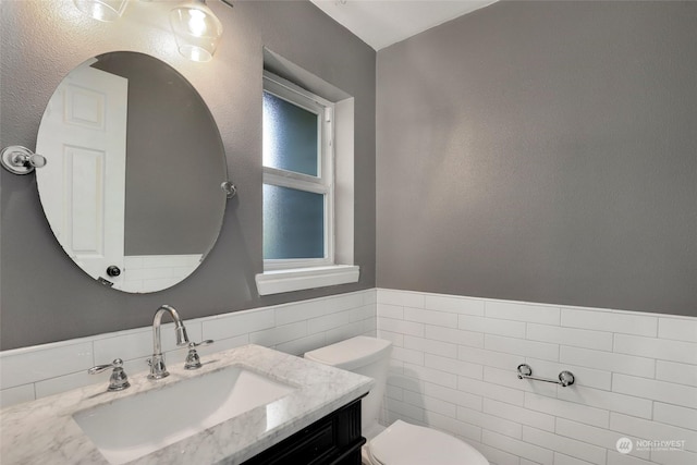 bathroom featuring tile walls, toilet, and vanity