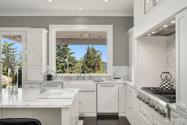 kitchen featuring sink, backsplash, white cabinetry, and stainless steel gas cooktop