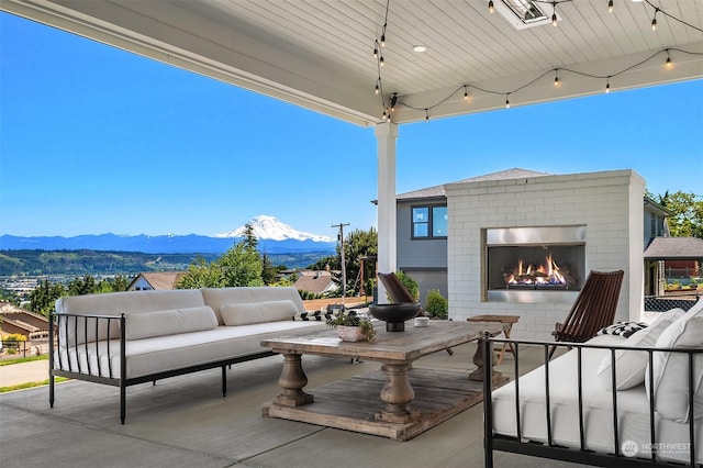 view of patio / terrace with a mountain view and an outdoor living space with a fireplace