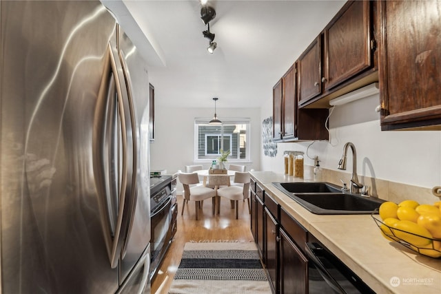 kitchen featuring pendant lighting, stainless steel refrigerator, rail lighting, sink, and light hardwood / wood-style floors