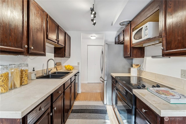 kitchen featuring dark brown cabinetry, rail lighting, sink, range with electric stovetop, and stainless steel dishwasher