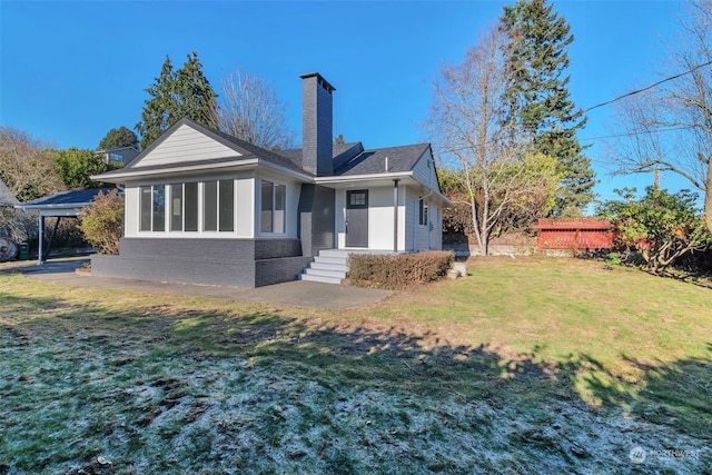 rear view of house with a lawn and a carport