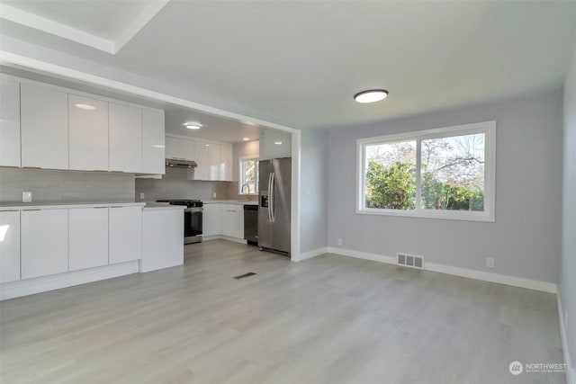 kitchen featuring backsplash, white cabinetry, appliances with stainless steel finishes, and light wood-type flooring